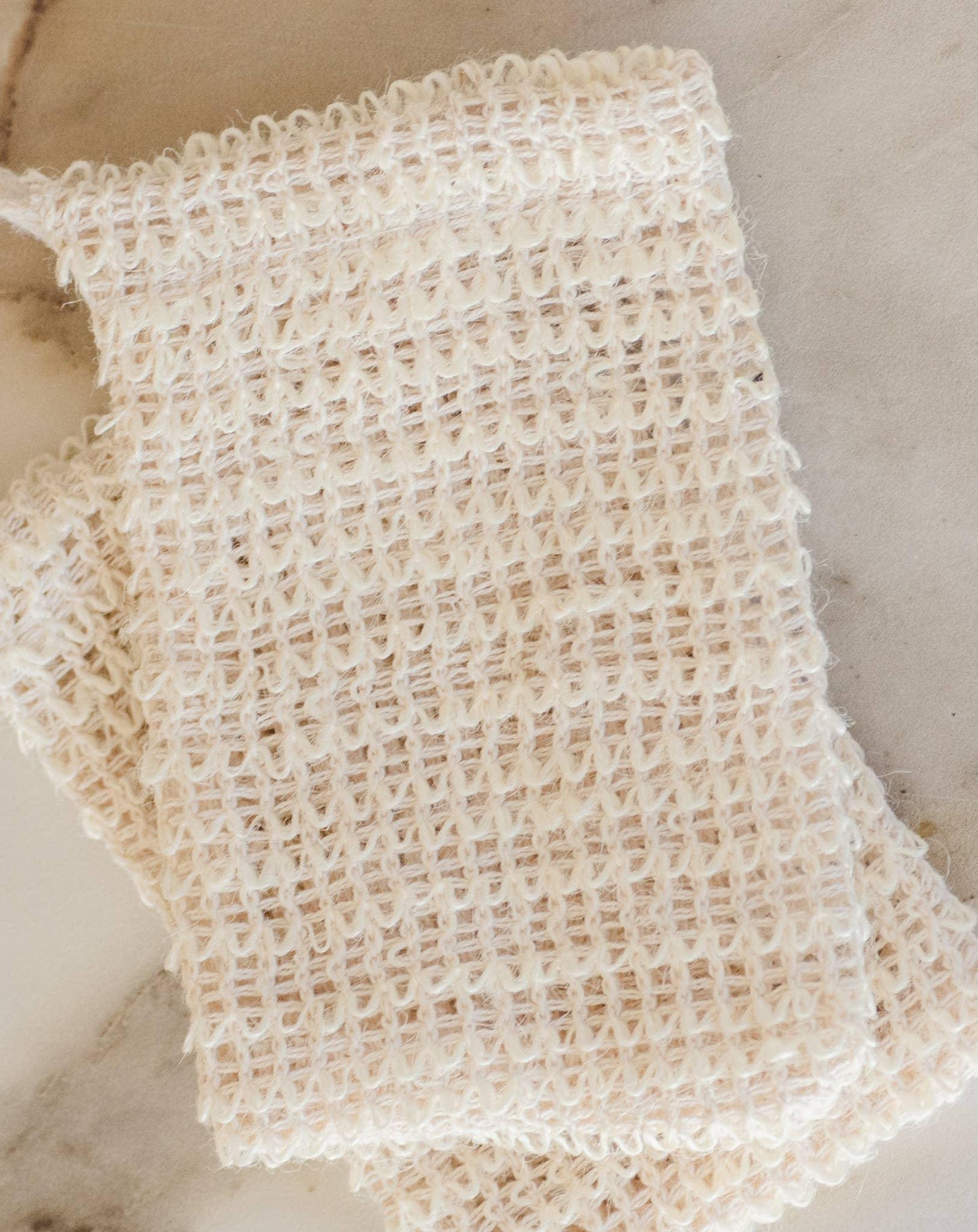 Close-up of a beige knitted fabric piece on a marble surface. Come see us at Awaken, Franklin, Tennessee