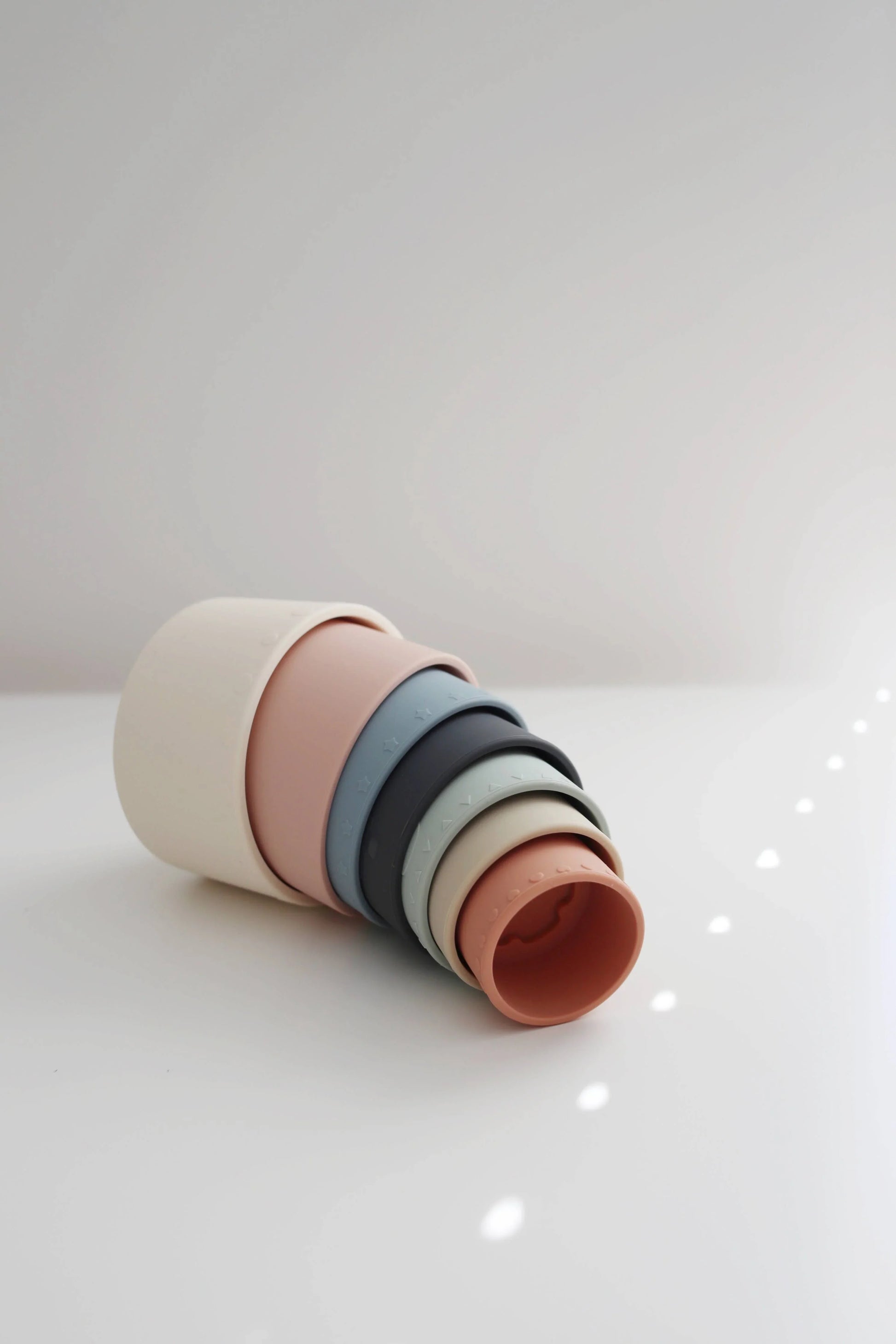 Set of pastel-colored silicone stacking cups on white surface with soft lighting. Come see us at Awaken, Franklin, Tennessee