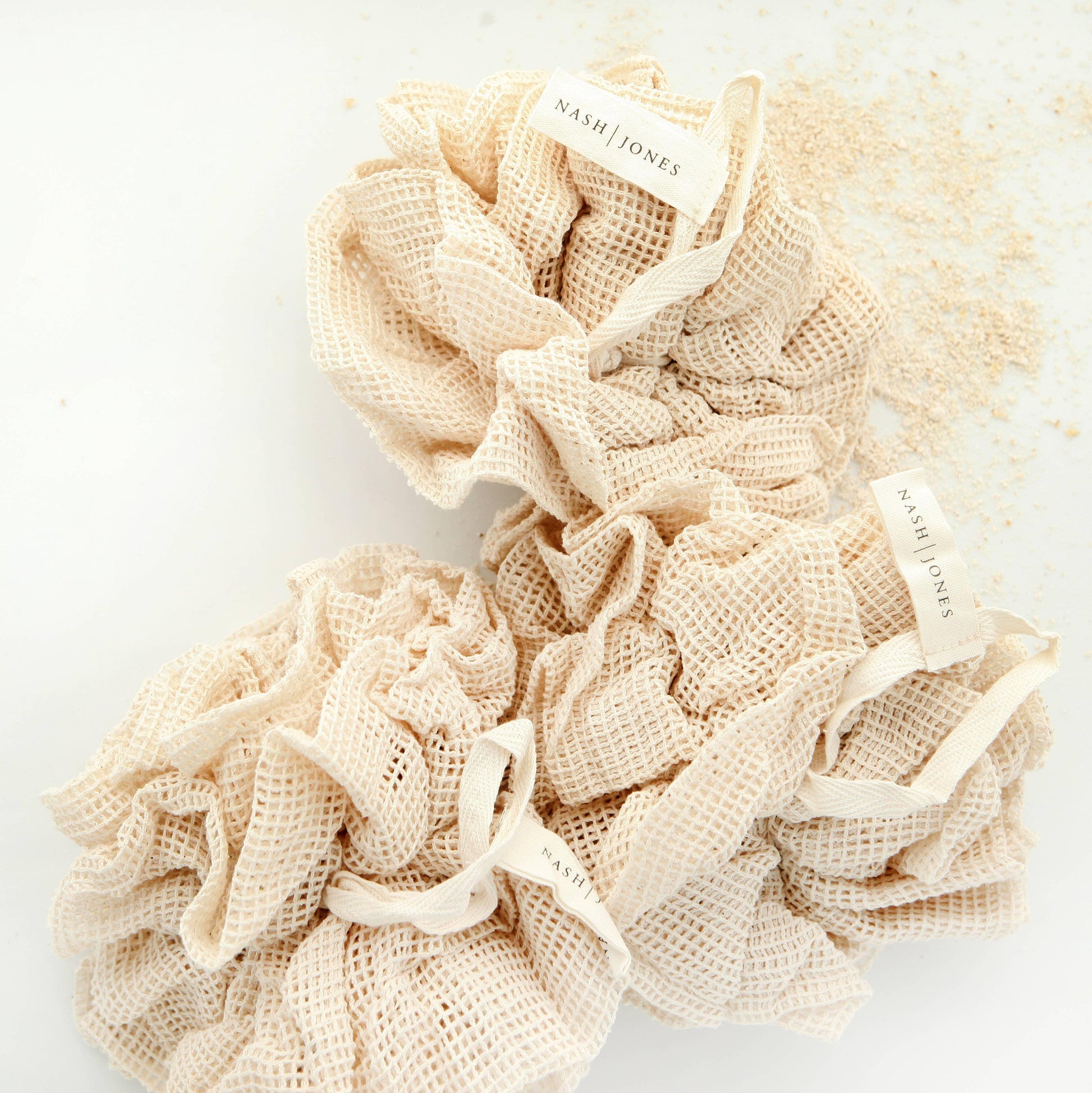 Nash Jones eco-friendly beige mesh scrunchies on white background with powder spills, Come see us at Awaken, Franklin, Tennessee