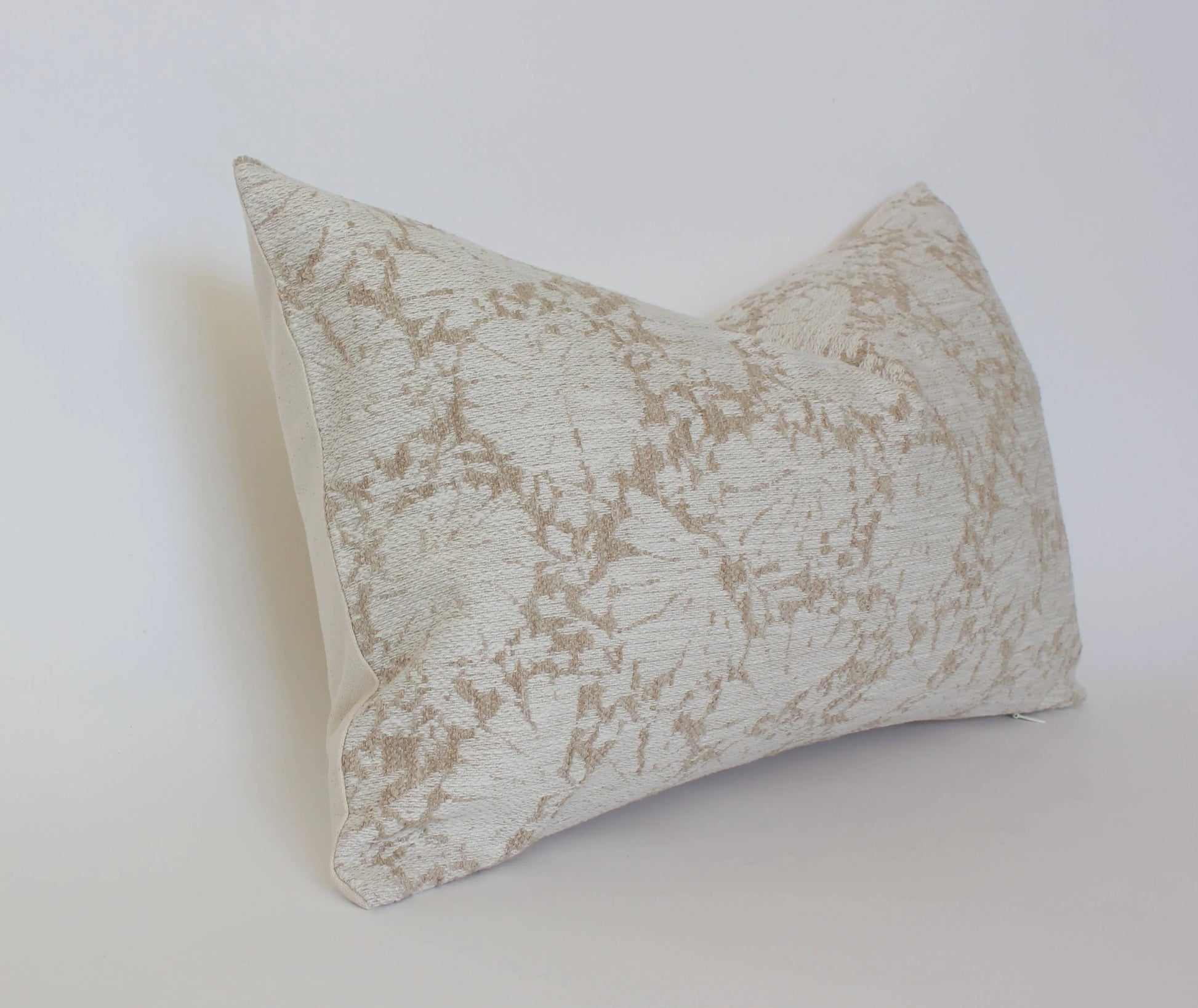 Beige decorative lumbar pillow with floral pattern on white background. Come see us at Awaken, Franklin, Tennessee
