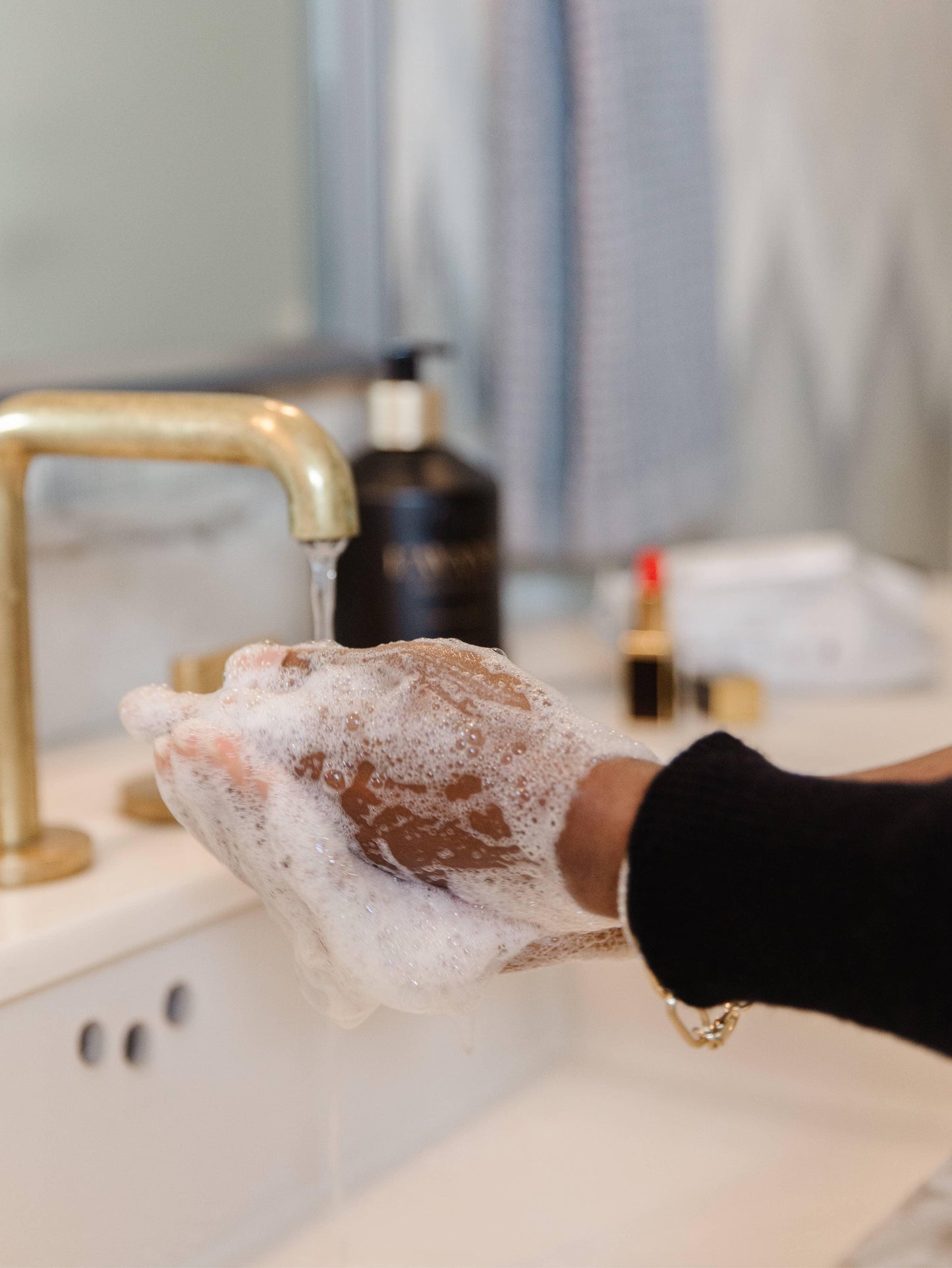 Washing hands with soap at a bathroom sink, gold faucet, Come see us at Awaken, Franklin, Tennessee
