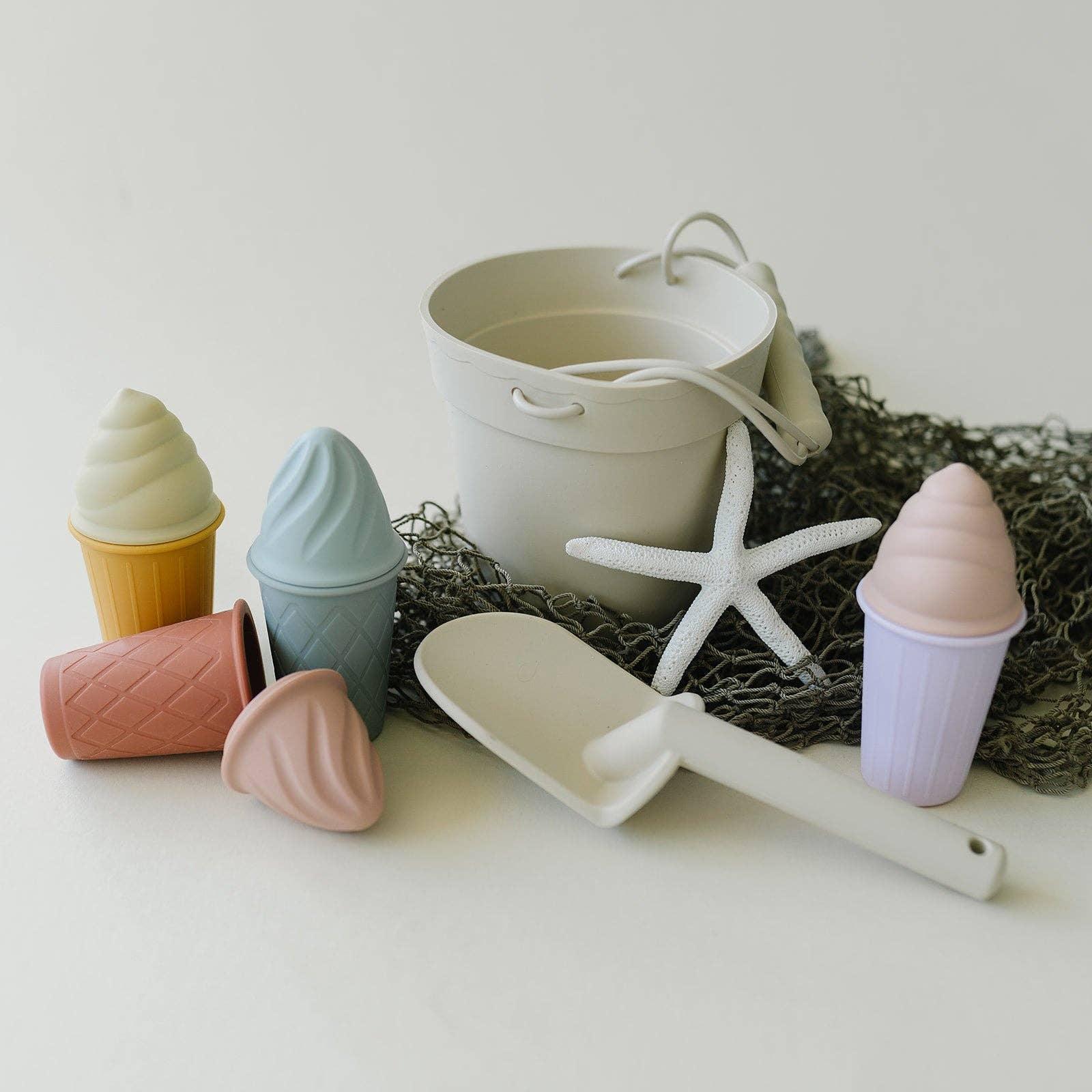 Pastel toy ice cream cones, white bucket, shovel, and starfish on netting, beach toy set. Come see us at Awaken, Franklin, Tennessee