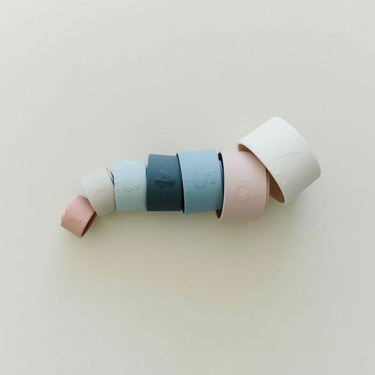 Stacked pastel silicone rings numbered 1 to 7 on white background, minimalist design. Come see us at Awaken, Franklin, Tennessee