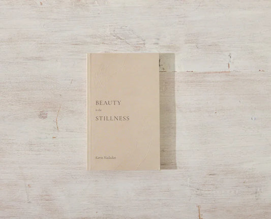 Book titled Beauty in the Stillness by Karin Haddon on a light wood surface. Come see us at Awaken, Franklin, Tennessee