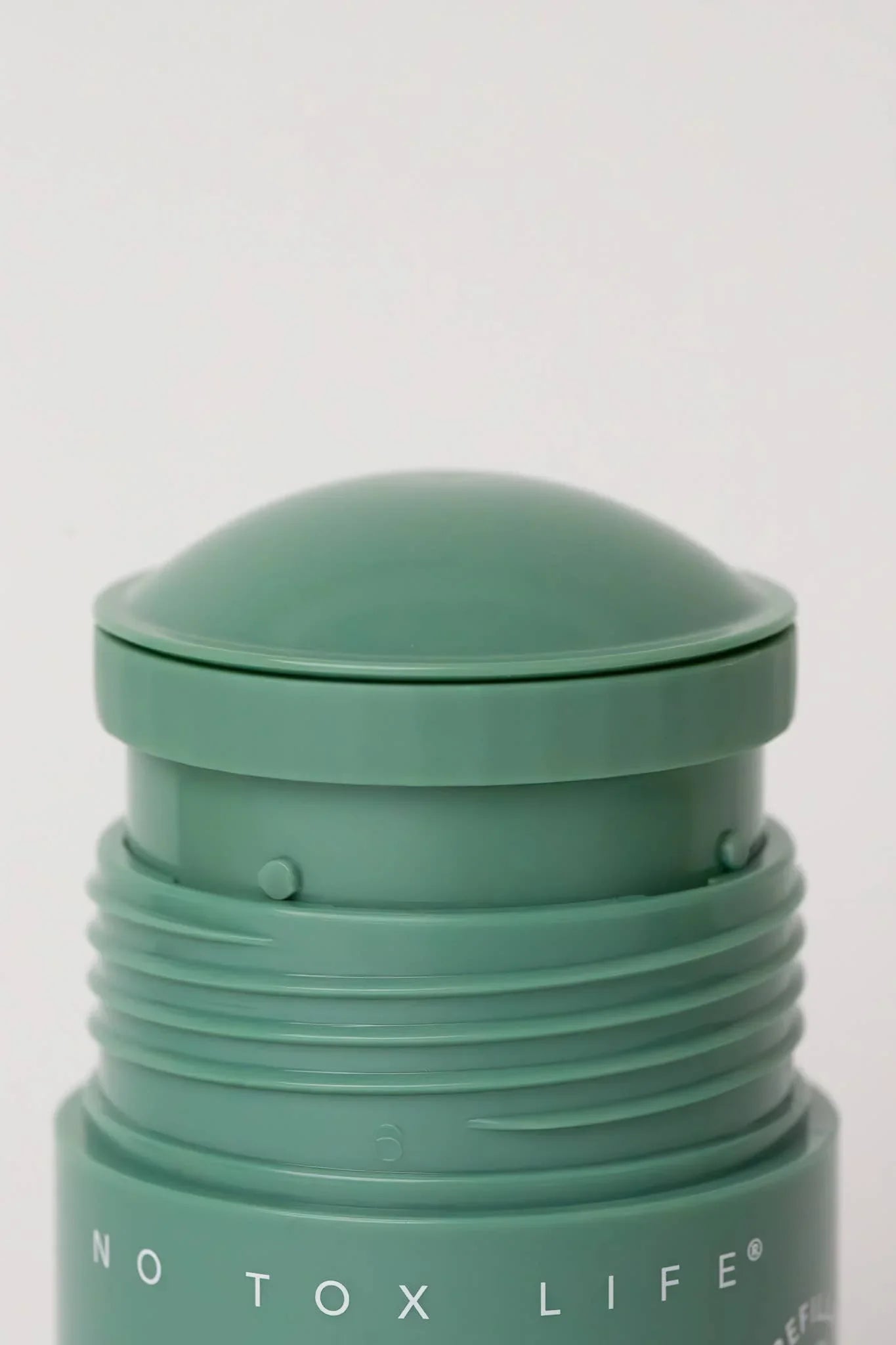 Close-up of green No Tox Life skincare stick with dome cap, minimalist design. Come see us at Awaken, Franklin, Tennessee