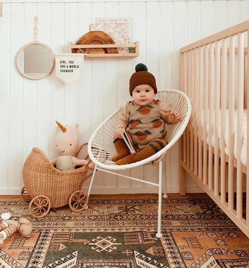 Baby in knit outfit and beanie sitting in chair, cozy nursery decor, Come see us at Awaken, Franklin, Tennessee