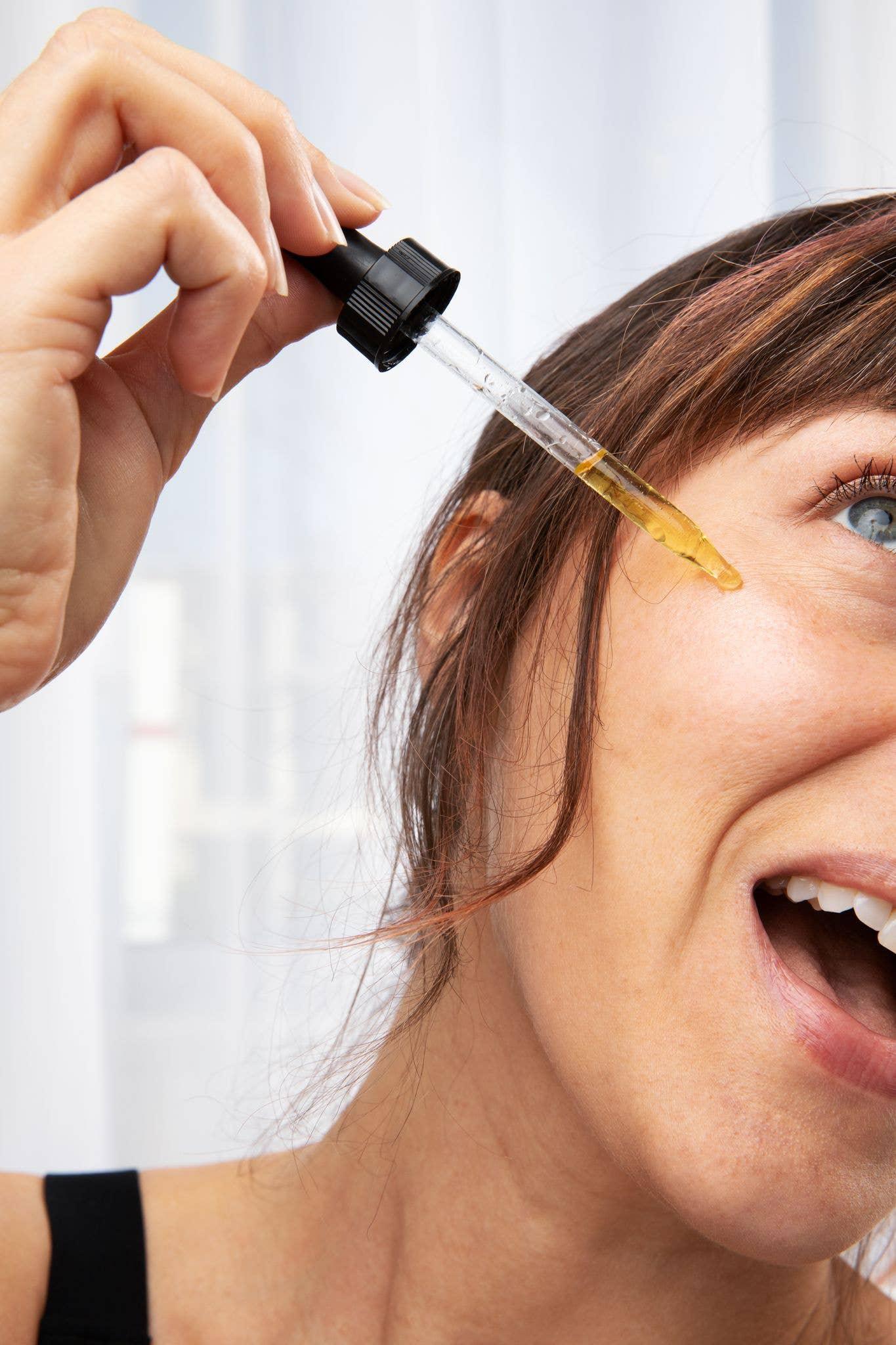 Woman applying facial serum with dropper for skin care, bright natural light, Come see us at Awaken, Franklin, Tennessee