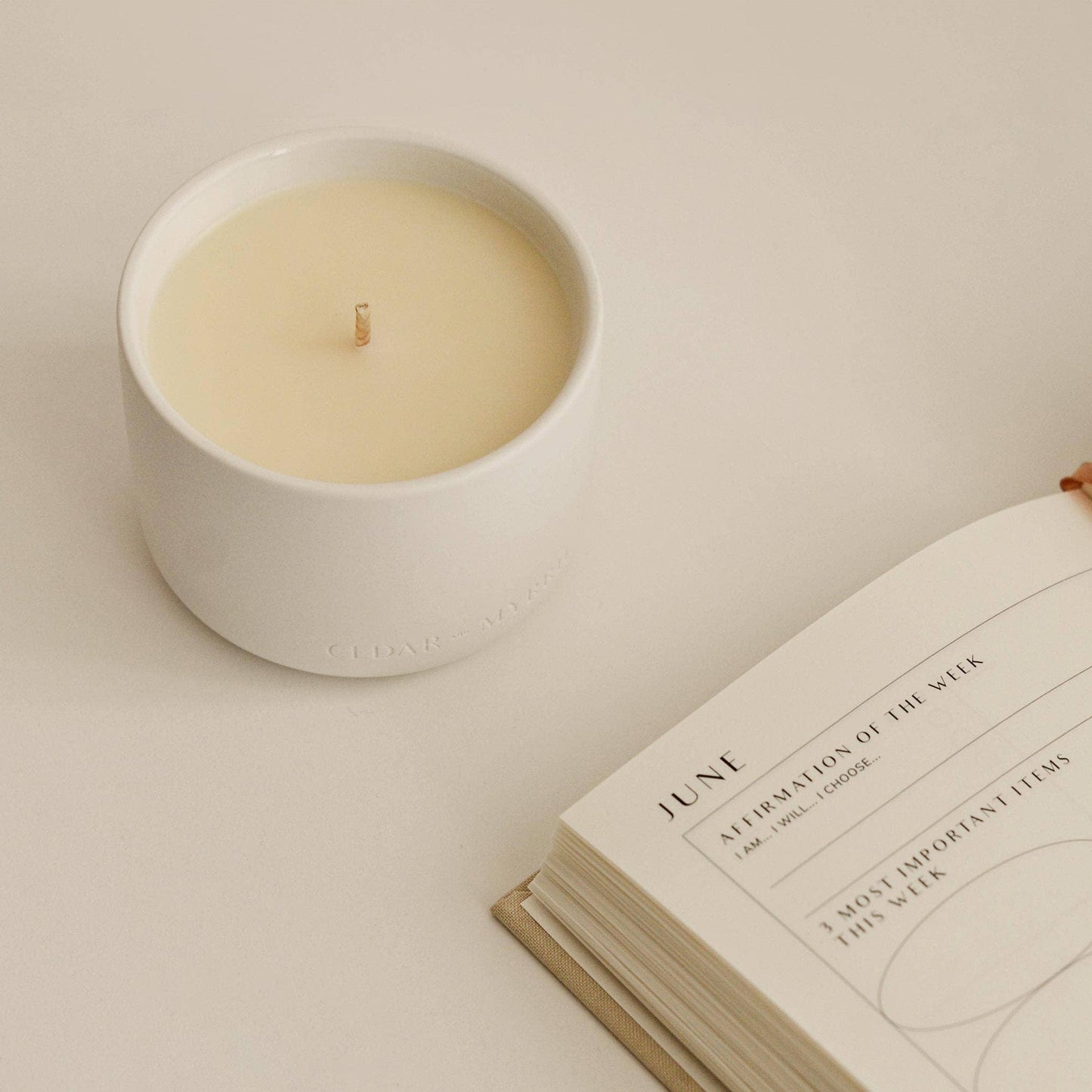 Minimalist white candle and open planner on desk, Come see us at Awaken, Franklin, Tennessee.