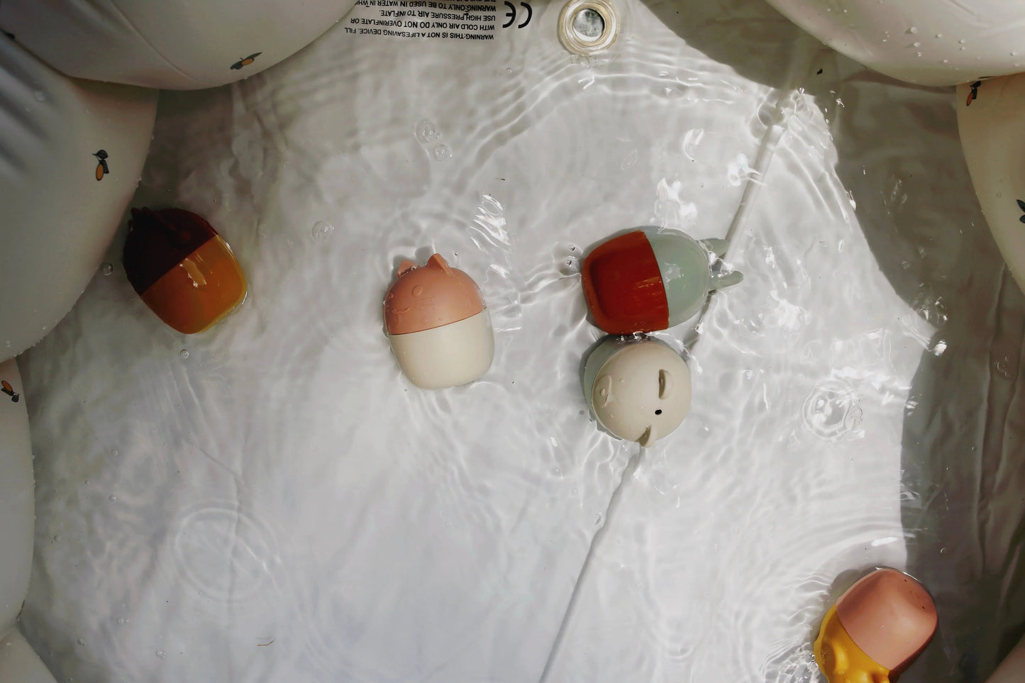 Floating cute animal-shaped bath toys in water with ripples, soft colors, Come see us at Awaken, Franklin, Tennessee