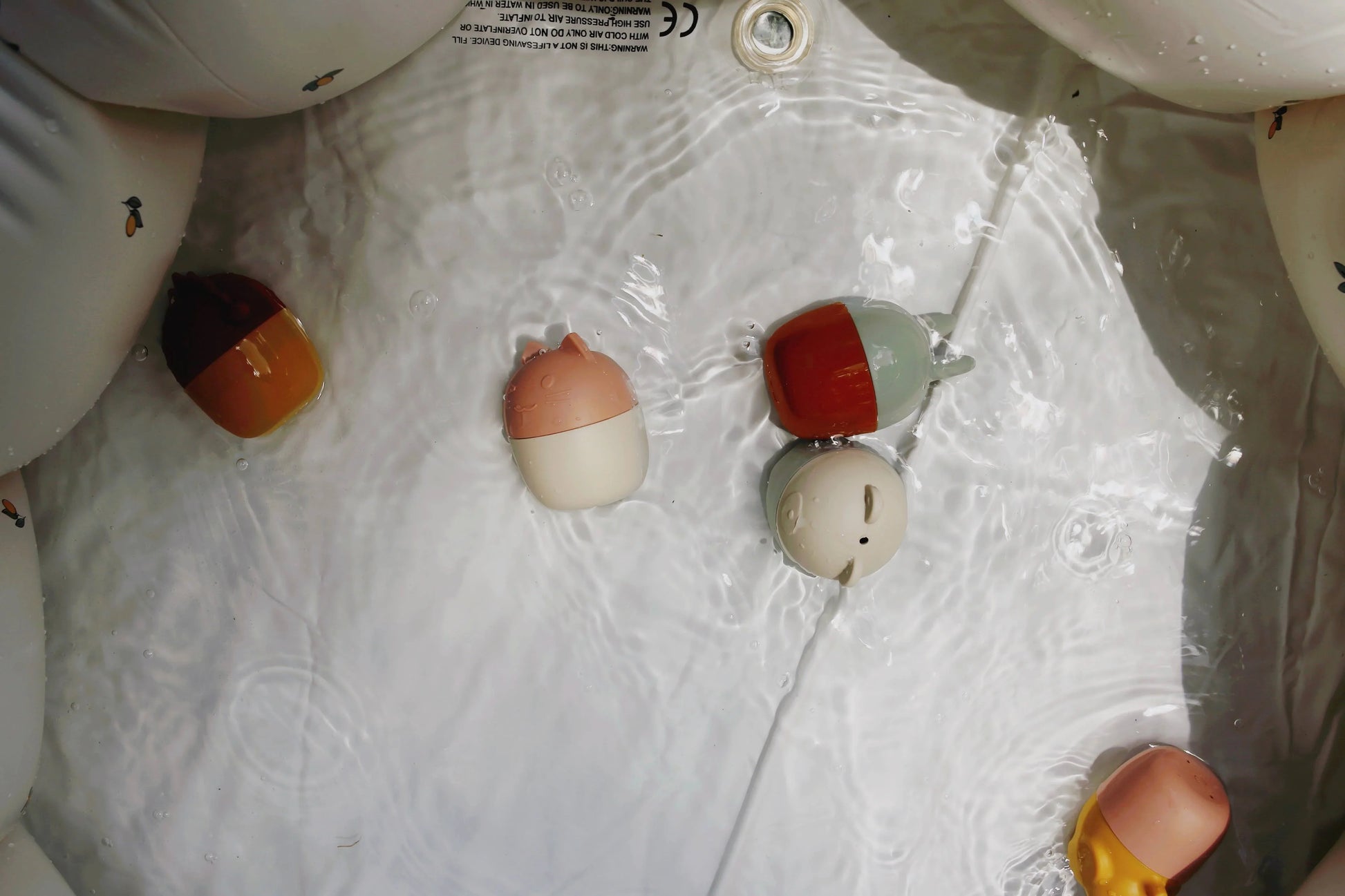 Floating cute animal-shaped bath toys in water with ripples, soft colors, Come see us at Awaken, Franklin, Tennessee