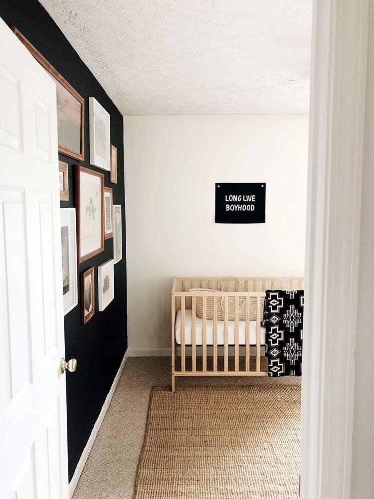 Minimalist nursery with crib, gallery wall, and 'Long Live Boyhood' sign. Come see us at Awaken, Franklin, Tennessee.