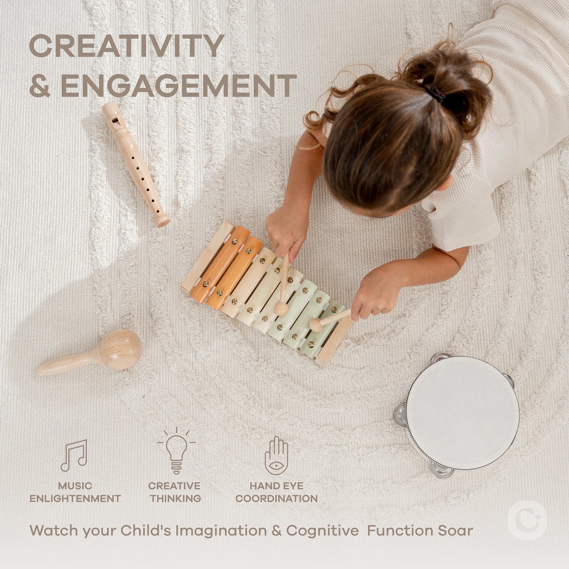Child playing xylophone on cream rug with wooden music toys, Come see us at Awaken, Franklin, Tennessee.