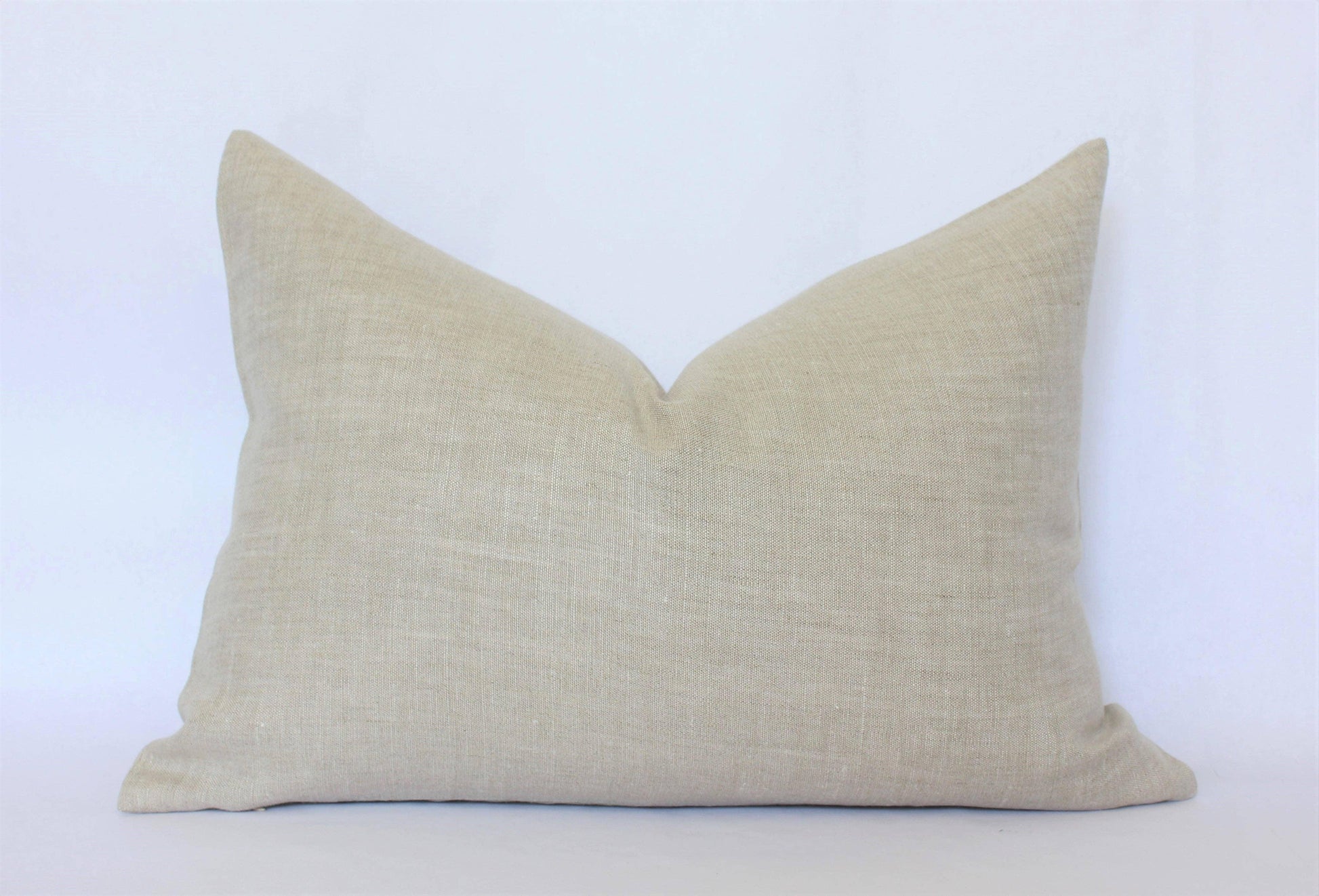 Beige linen pillow with textured fabric on white background. Come see us at Awaken, Franklin, Tennessee