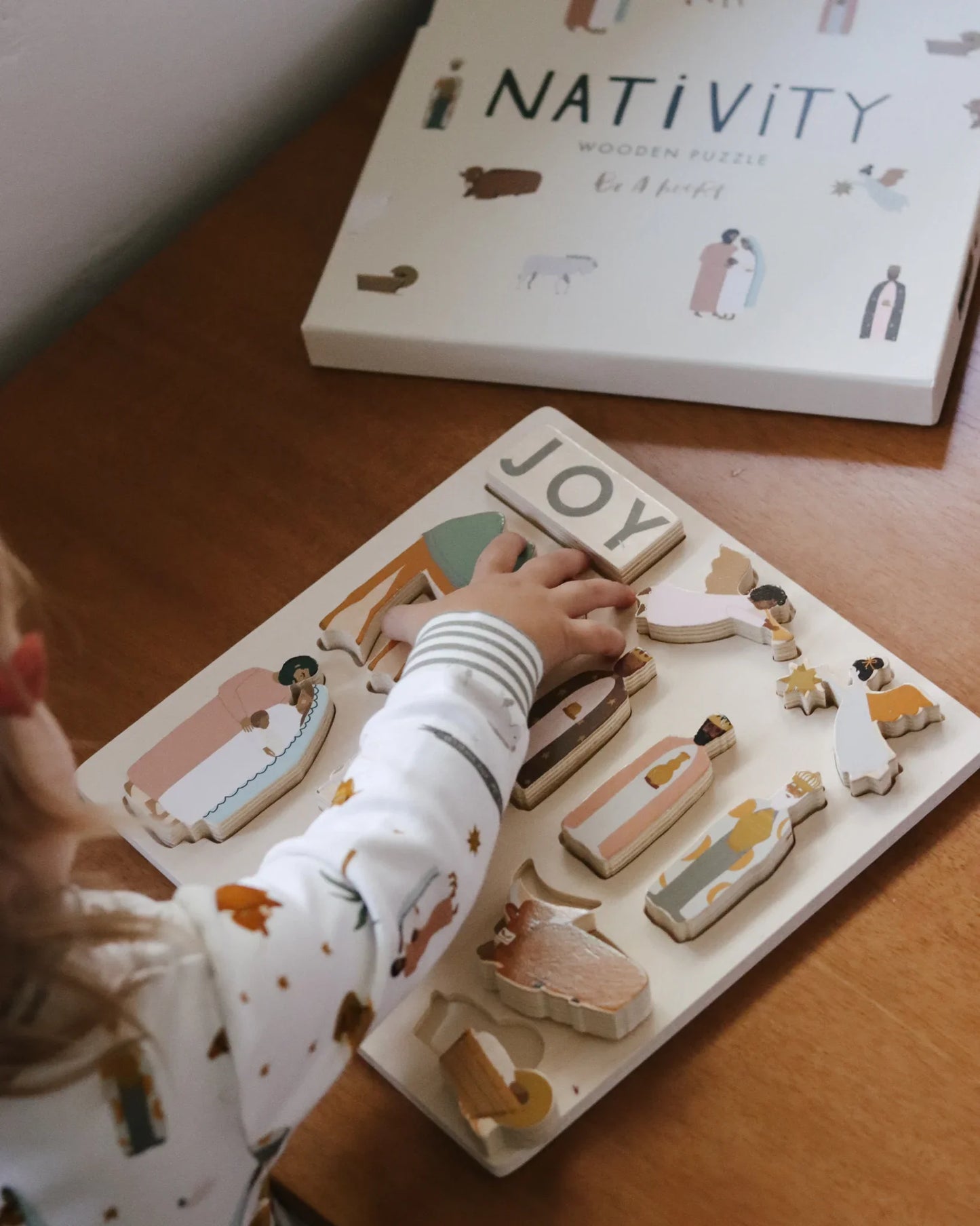 Child assembling wooden nativity puzzle on table, Come see us at Awaken, Franklin, Tennessee