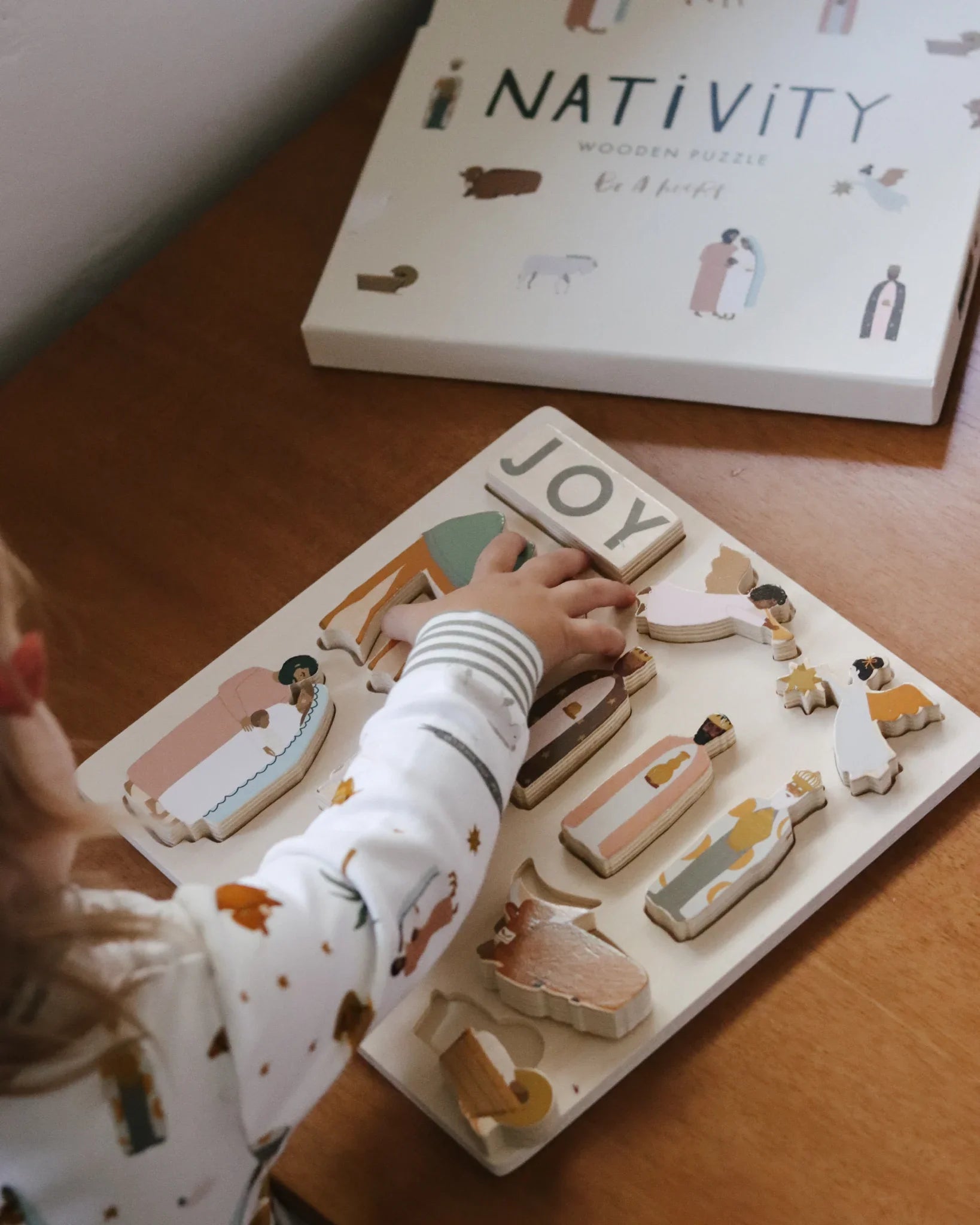 Child assembling wooden nativity puzzle on table, Come see us at Awaken, Franklin, Tennessee
