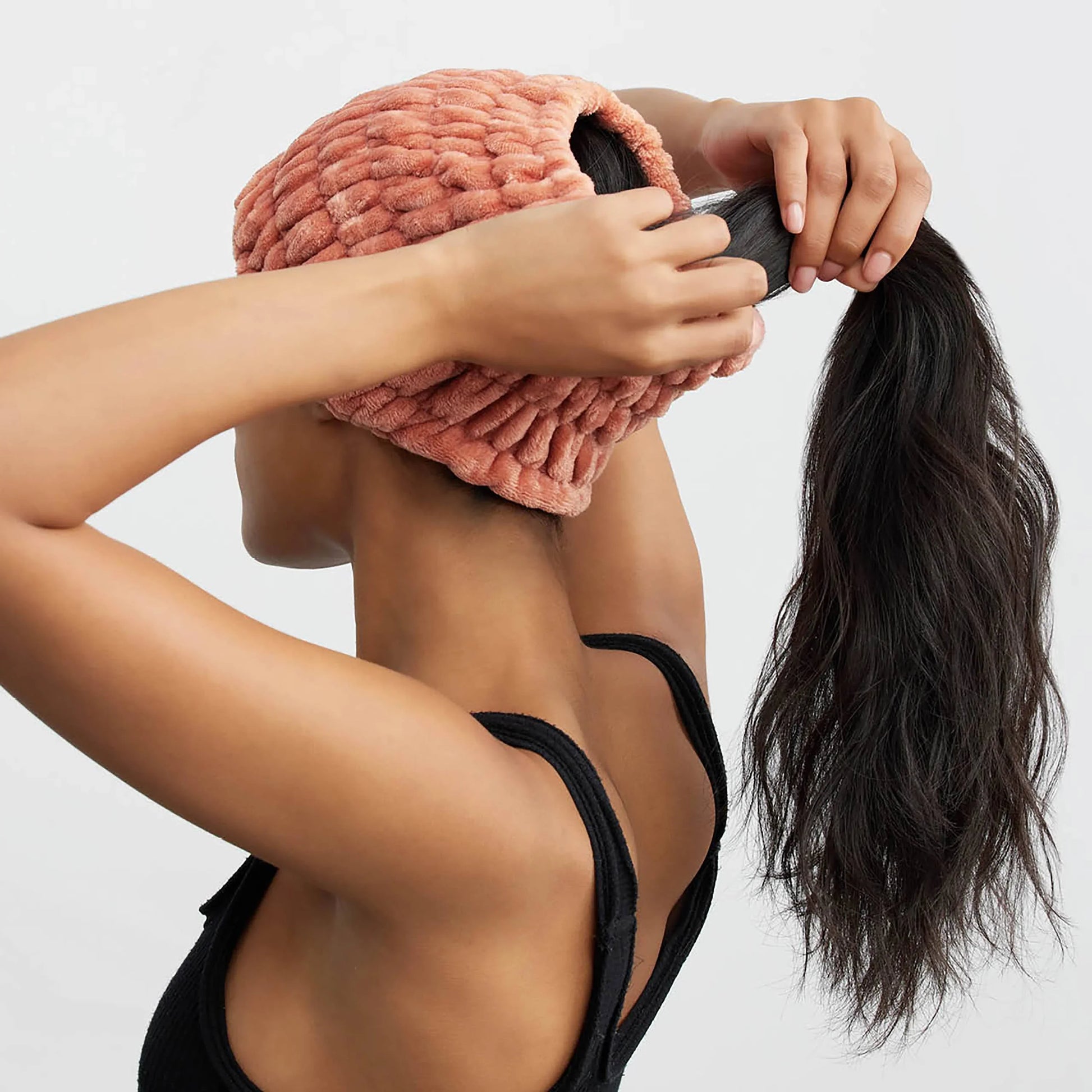 Woman in black tank top wearing textured pink velvet hat, holding long dark ponytail. Come see us at Awaken, Franklin, Tennessee
