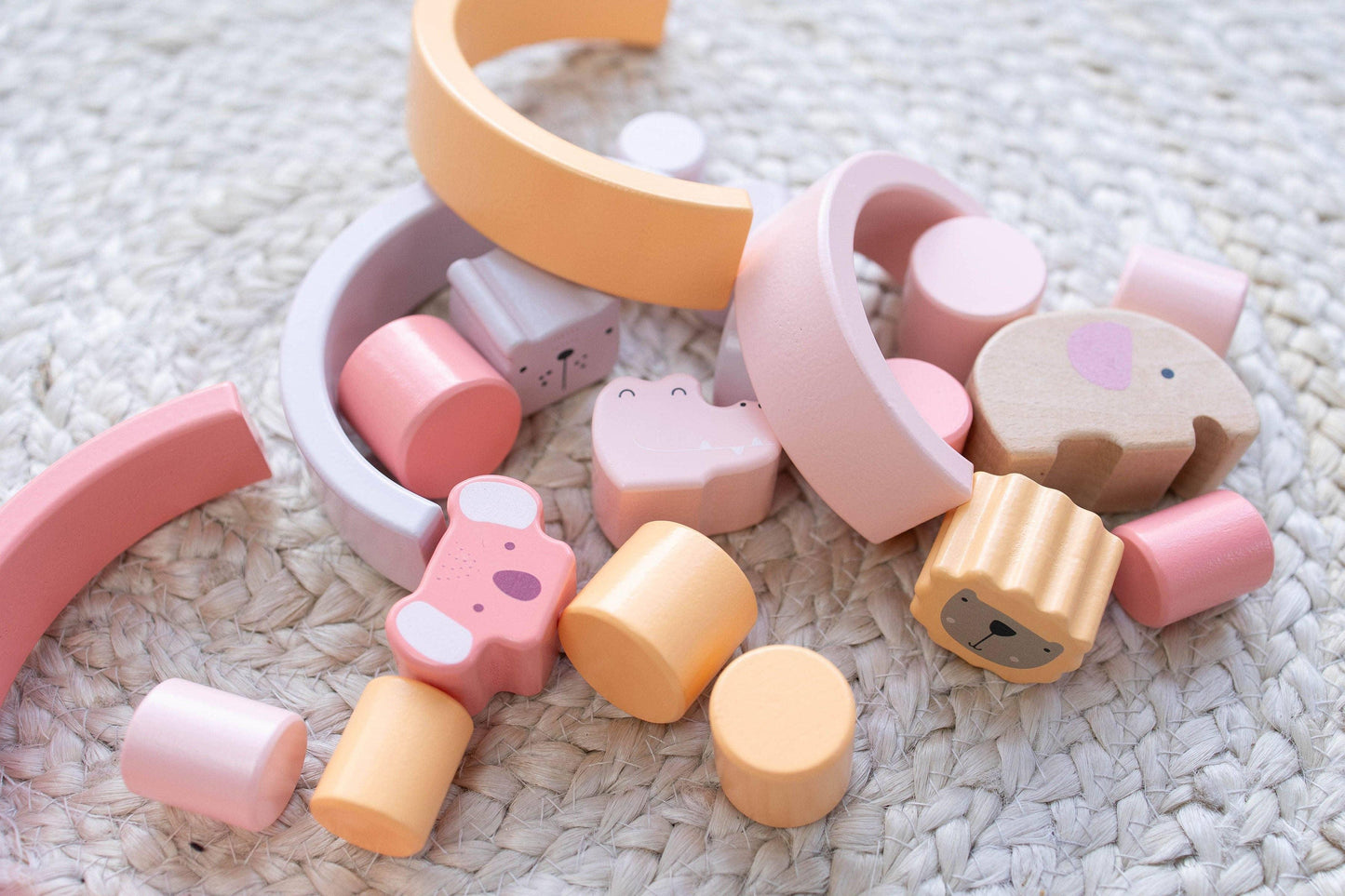 Colorful wooden animal and geometric toy blocks on woven rug, pastel pink and orange. Come see us at Awaken, Franklin, Tennessee