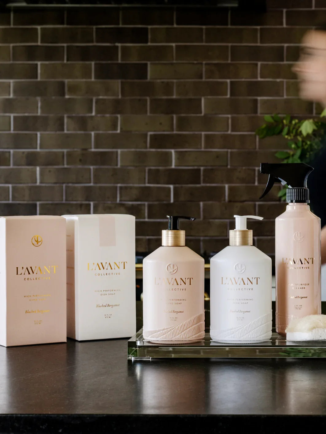 L'AVANT Collective hand soap, dish soap, and cleaner on black counter, brick wall background. Come see us at Awaken, Franklin, Tennessee.