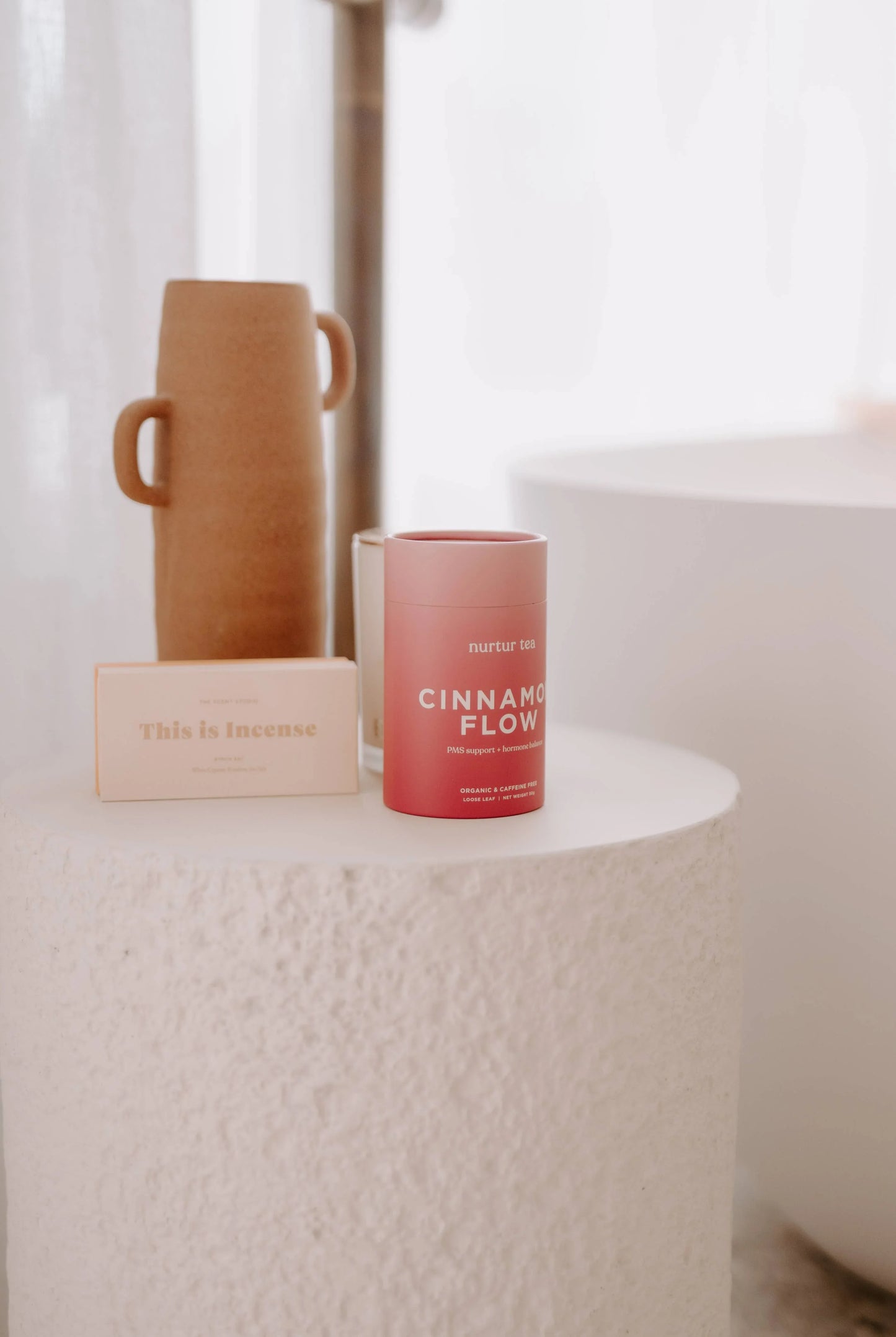 Natural incense and cinnamon flow tea with brown vase on textured white table Come see us at Awaken, Franklin, Tennessee