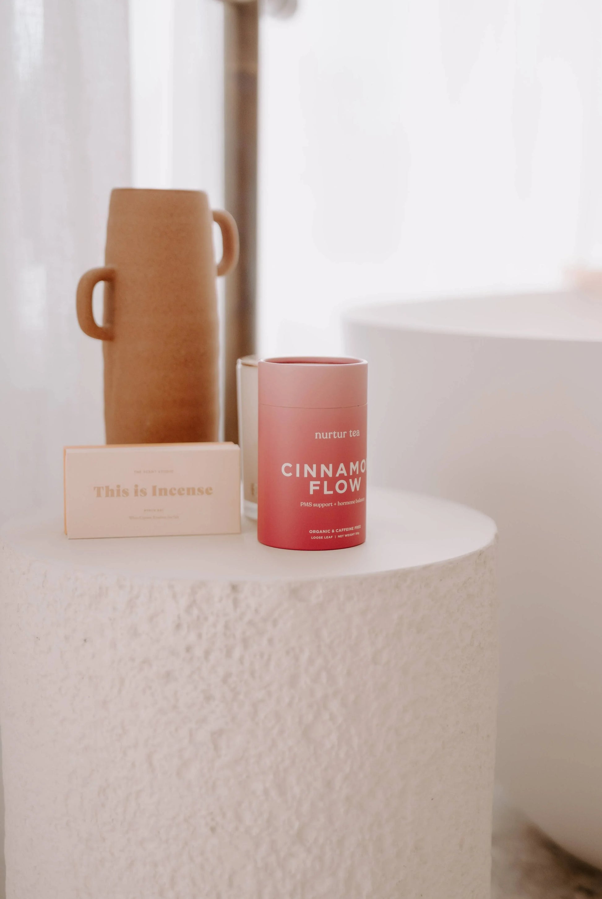 Natural incense and cinnamon flow tea with brown vase on textured white table Come see us at Awaken, Franklin, Tennessee