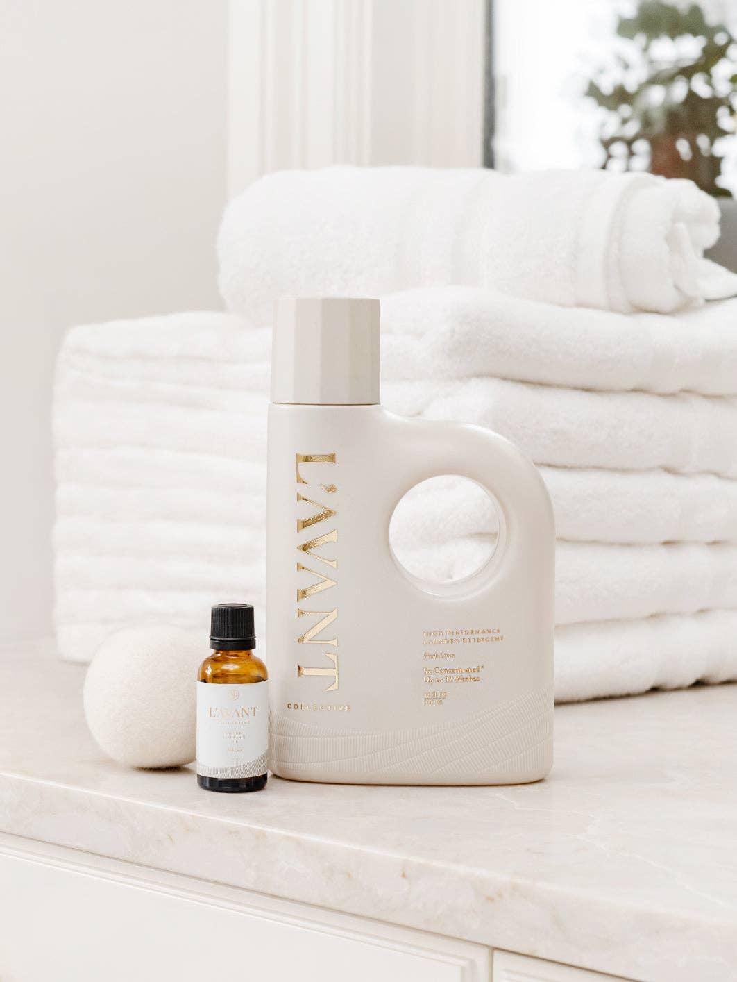 L'AVANT laundry detergent, essential oil bottle, and wool dryer ball on marble with white towels, Come see us at Awaken, Franklin, Tennessee
