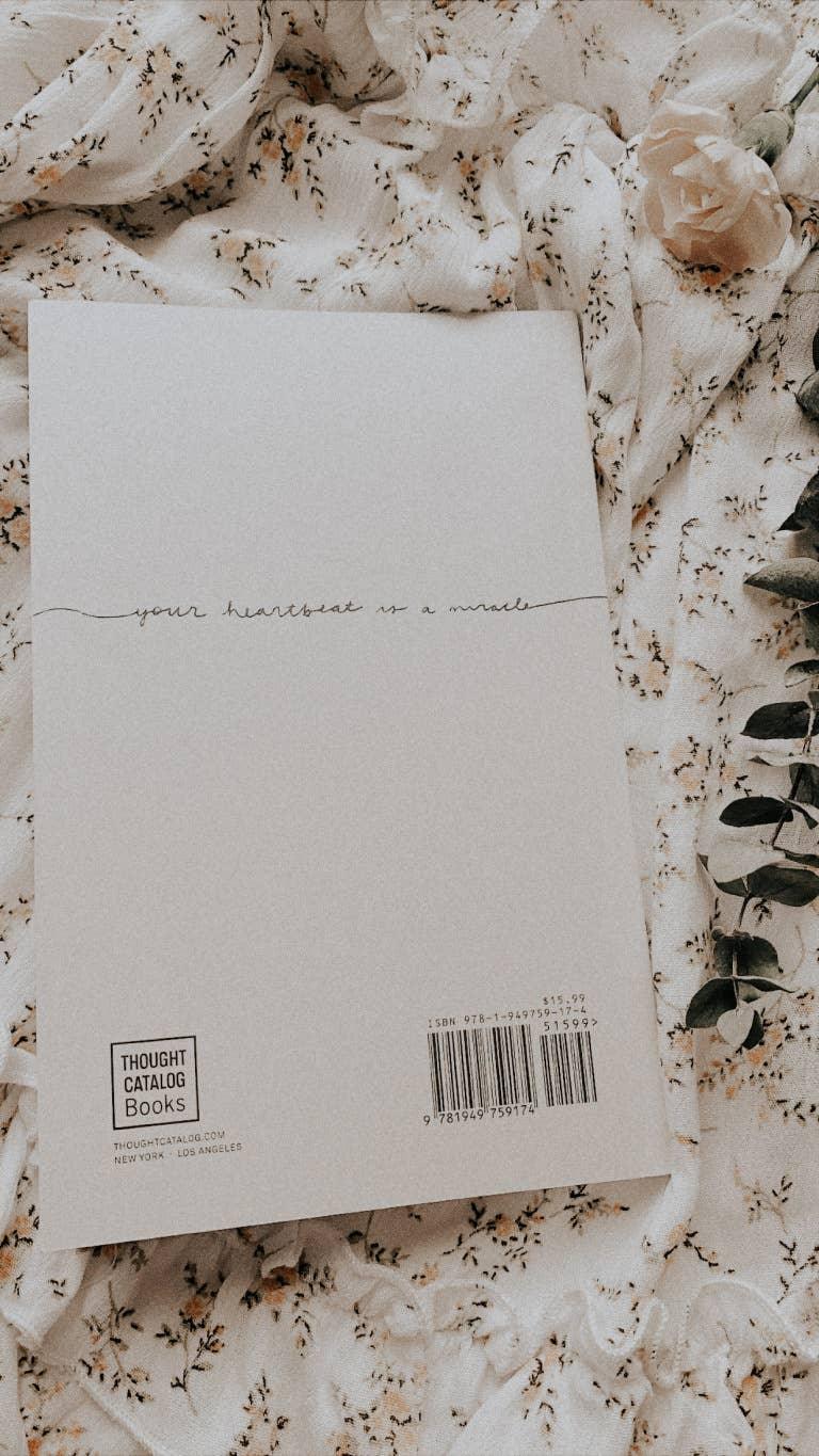 Back cover of Thought Catalog book "your heartbeat is a miracle" on floral fabric with a pale rose, Come see us at Awaken, Franklin, Tennessee