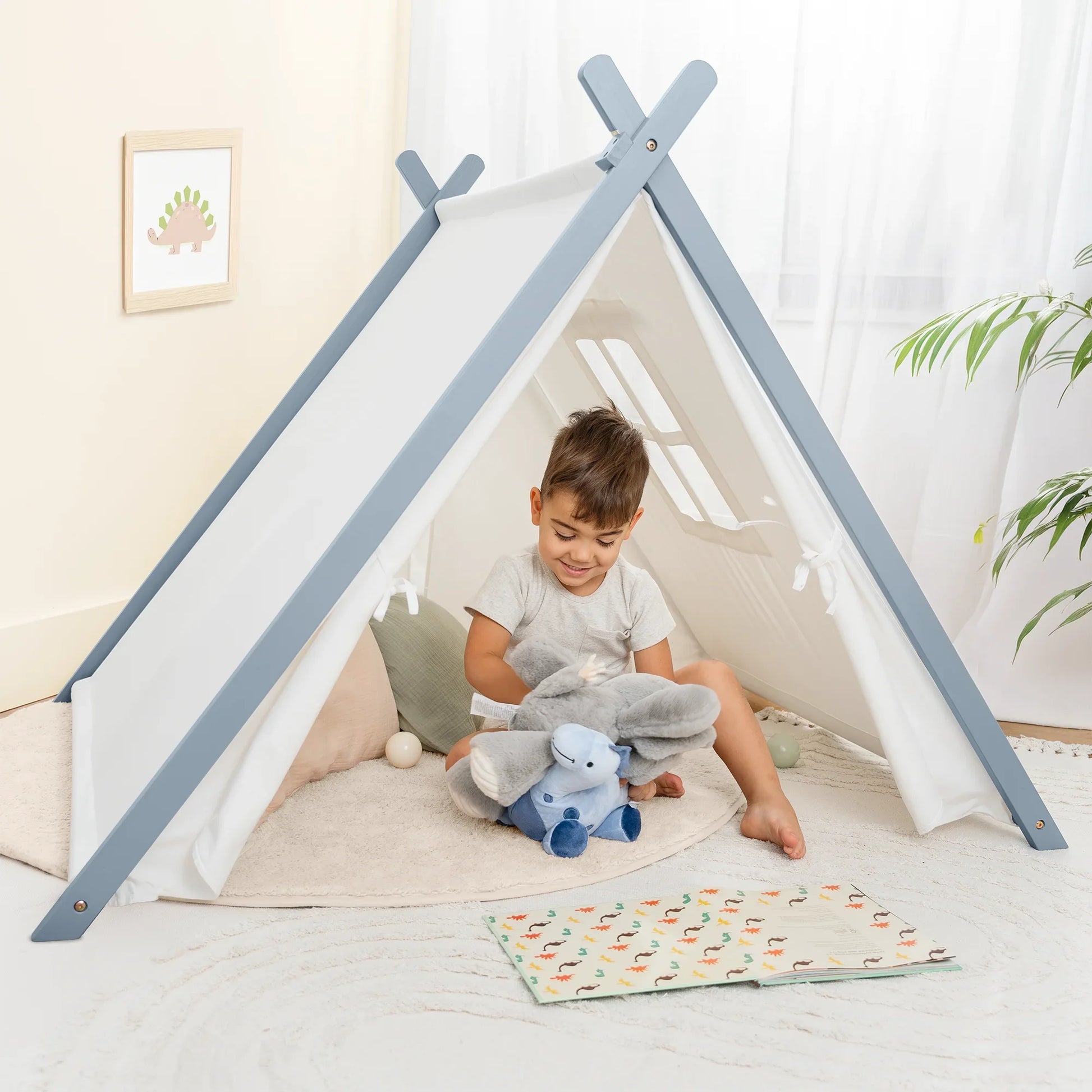 Smiling boy plays with elephant plush in kids teepee tent, cozy decor, Come see us at Awaken, Franklin, Tennessee