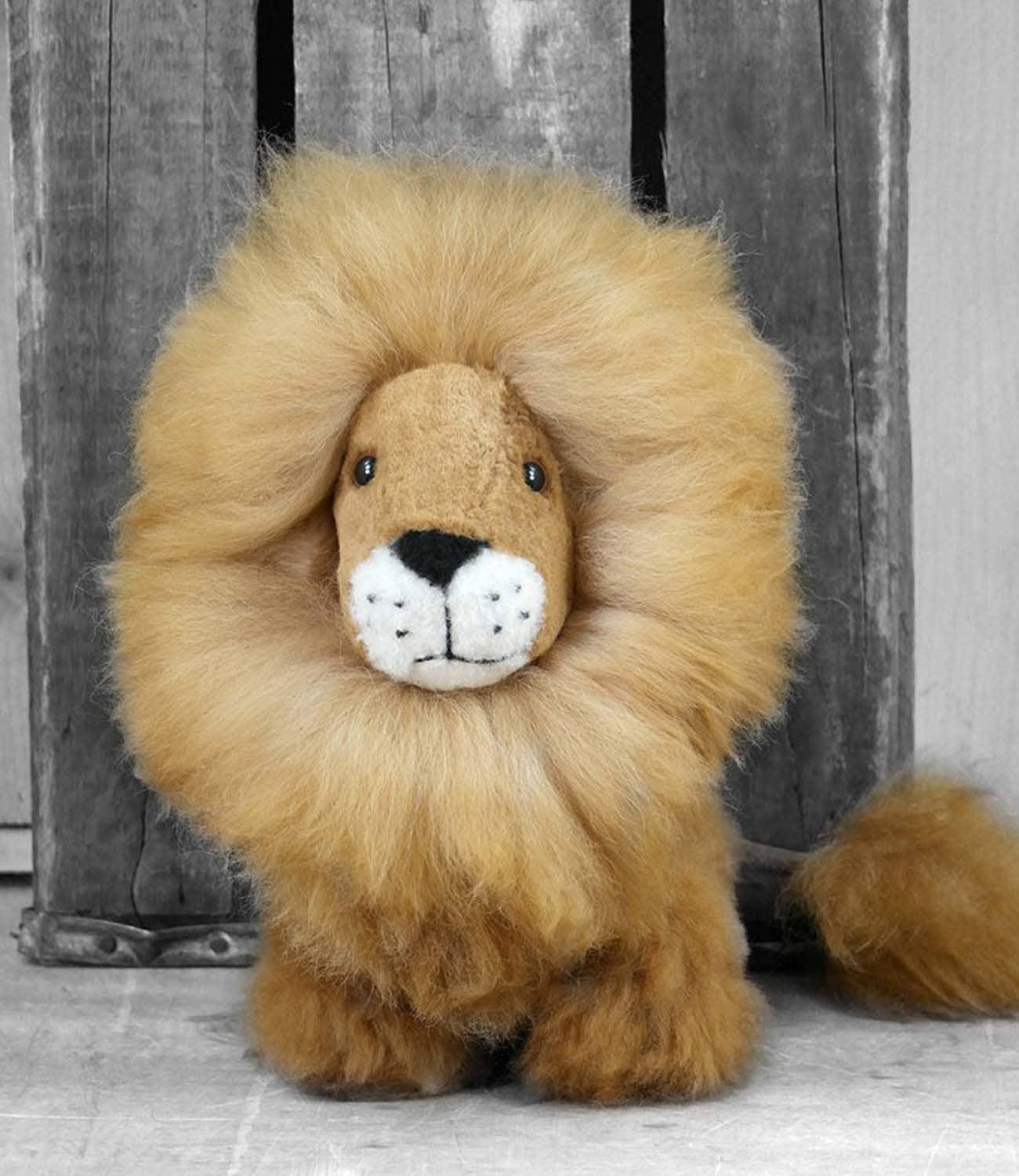 Fluffy stuffed lion toy with thick mane standing indoors on wooden floor Come see us at Awaken, Franklin, Tennessee