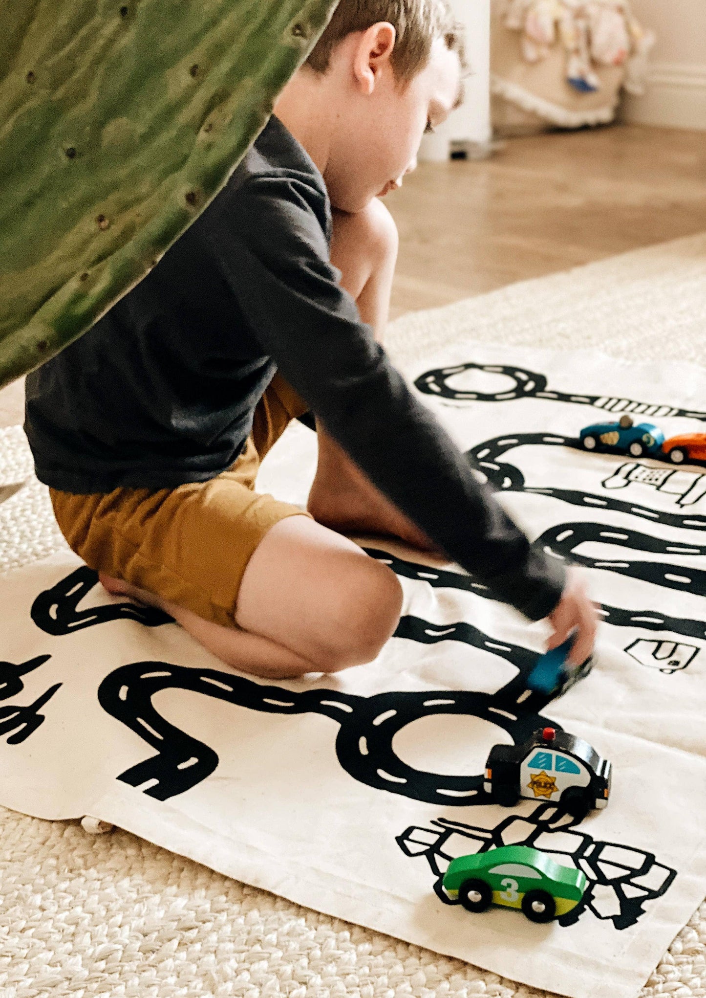 Young boy playing with wooden toy cars on a playmat road. Come see us at Awaken, Franklin, Tennessee.