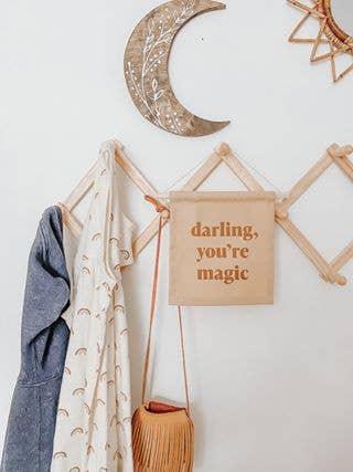 Decorative wooden moon, fabric banner with 'darling, you're magic', and hanging scarves and bag on wall hooks. Come see us at Awaken, Franklin, Tennessee