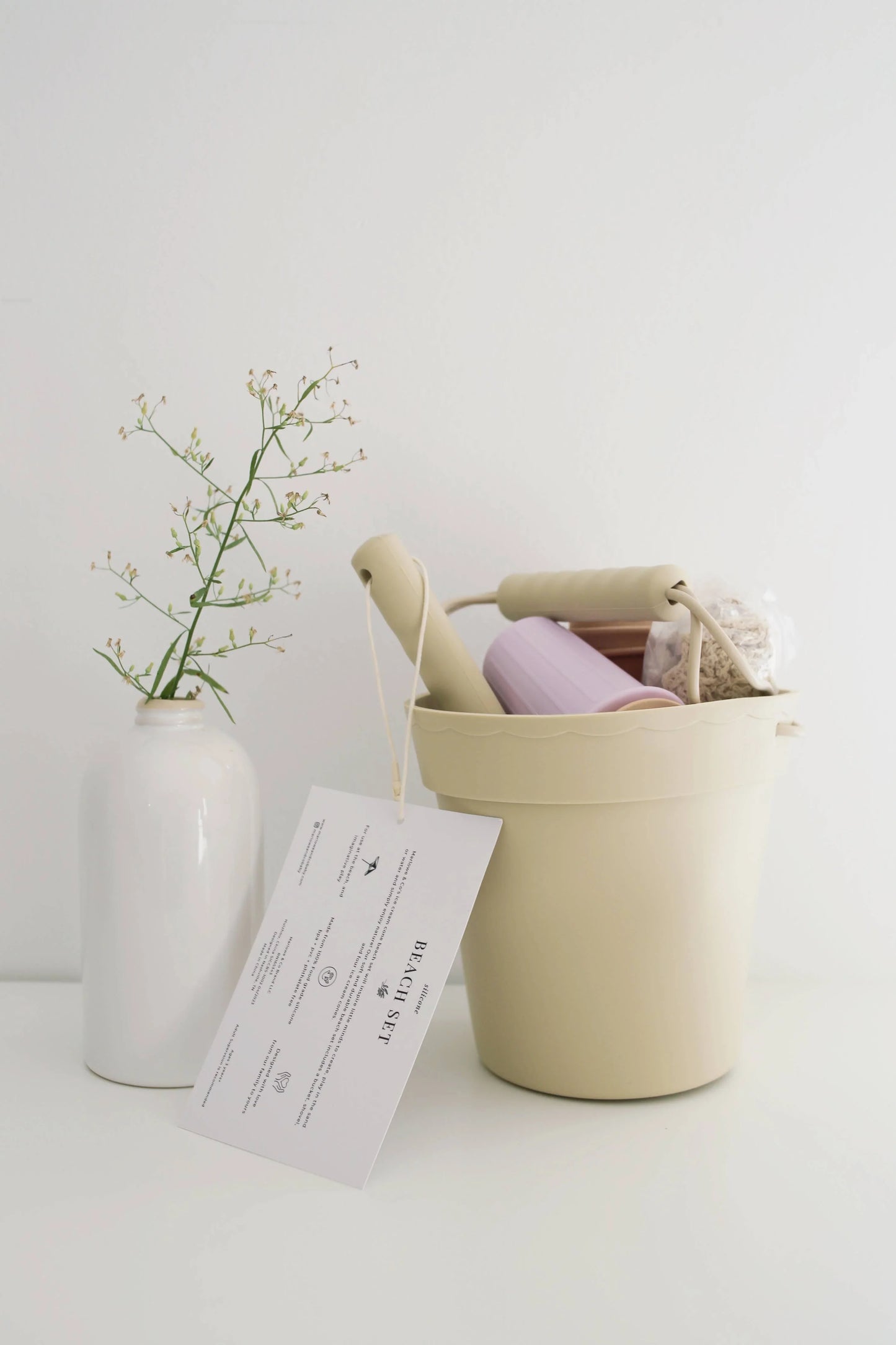 Beige beach toy bucket with rollers and soap, white vase with delicate twig, minimal decor. Come see us at Awaken, Franklin, Tennessee