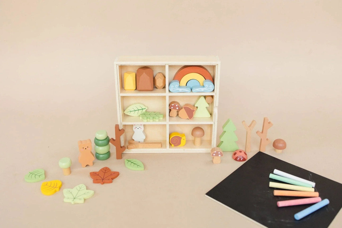 Wooden nature-themed toy set with leaves, trees, animals, and chalk on beige background. Come see us at Awaken, Franklin, Tennessee