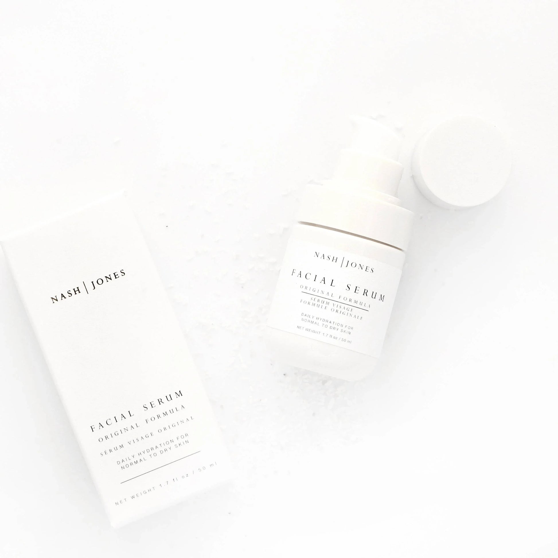 Nash | Jones facial serum bottle and box on white background with sea salt flakes, skincare product. Come see us at Awaken, Franklin, Tennessee