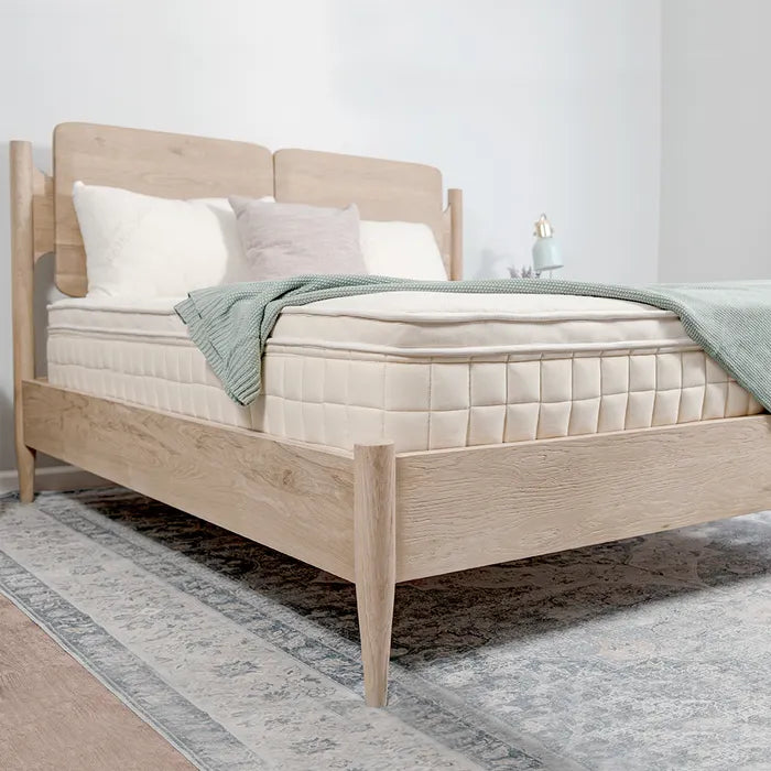 Modern light wood bed frame with plush mattress and pillows in bright bedroom, Come see us at Awaken, Franklin, Tennessee