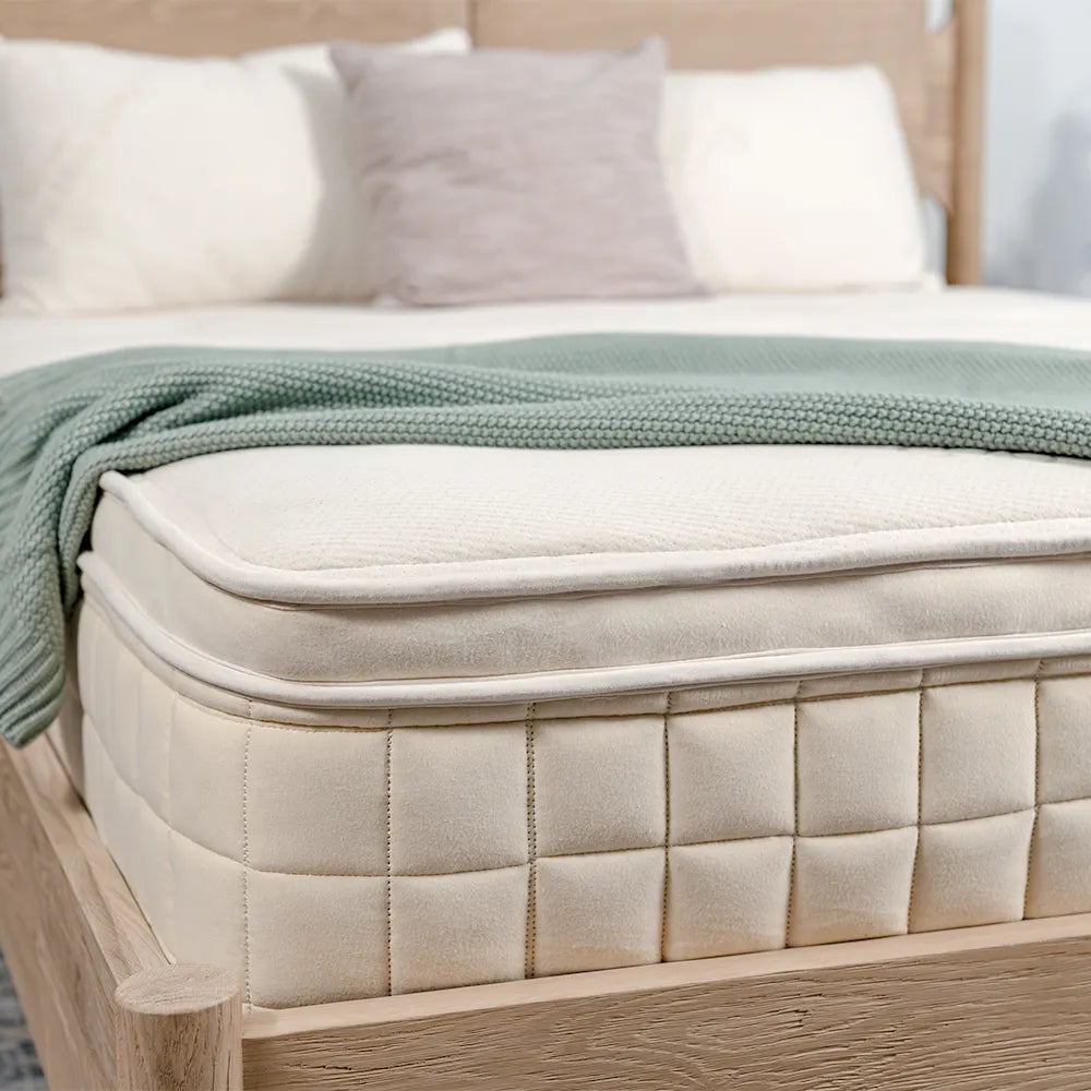Luxury mattress with green knit blanket on wooden bed frame, Come see us at Awaken, Franklin, Tennessee