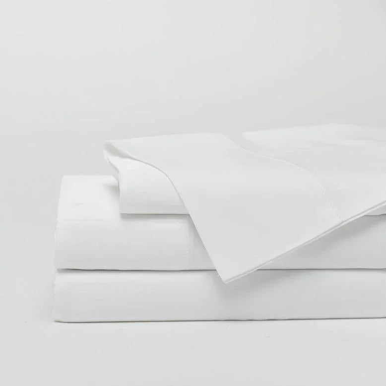 Stack of soft, white bed sheets neatly folded on a white background. Come see us at Awaken, Franklin, Tennessee